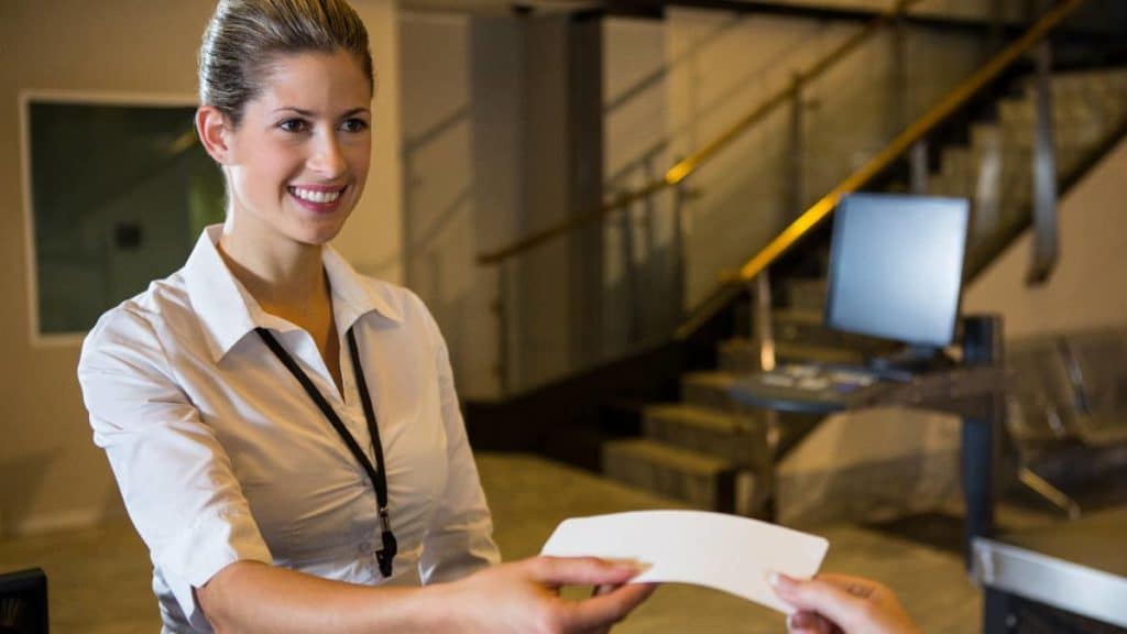 Assistente de portos e aeroportos a entregar um documento a um passageiro num átrio