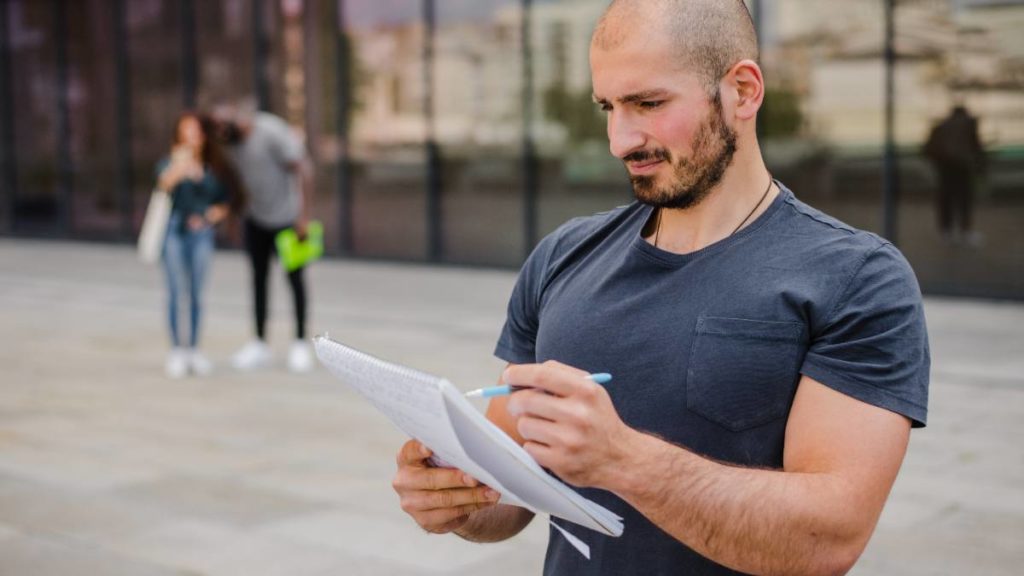 Homem a escrever num bloco de notas num recinto desportivo ao ar livre