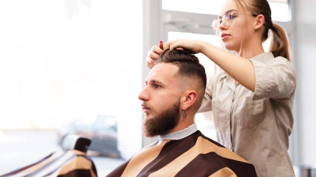 Cabeleireira a fazer um penteado a um cliente homem num salão de cabeleireiro