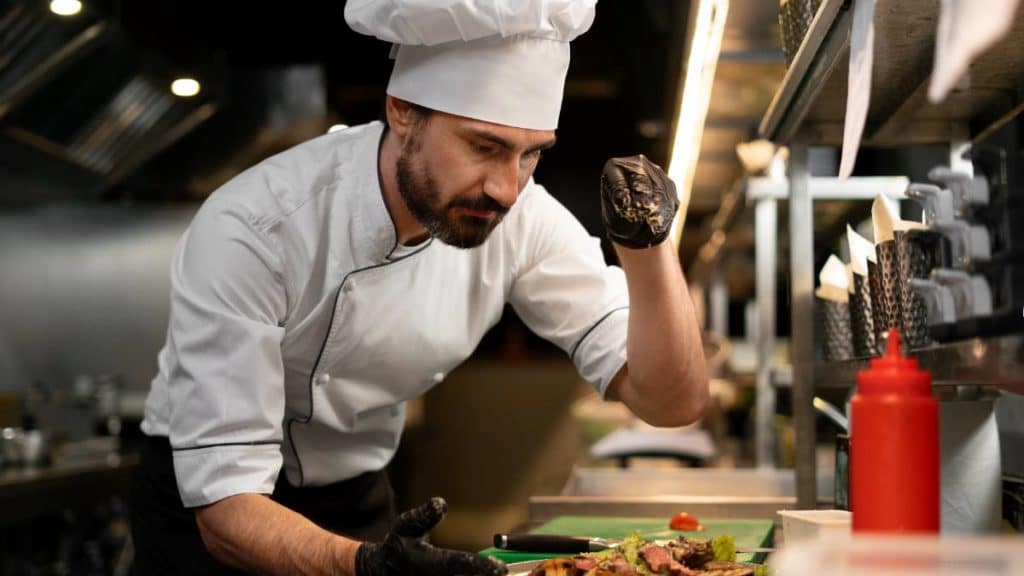 Chefe de cozinha a preparar e emplatar um prato de carne numa cozinha profissional