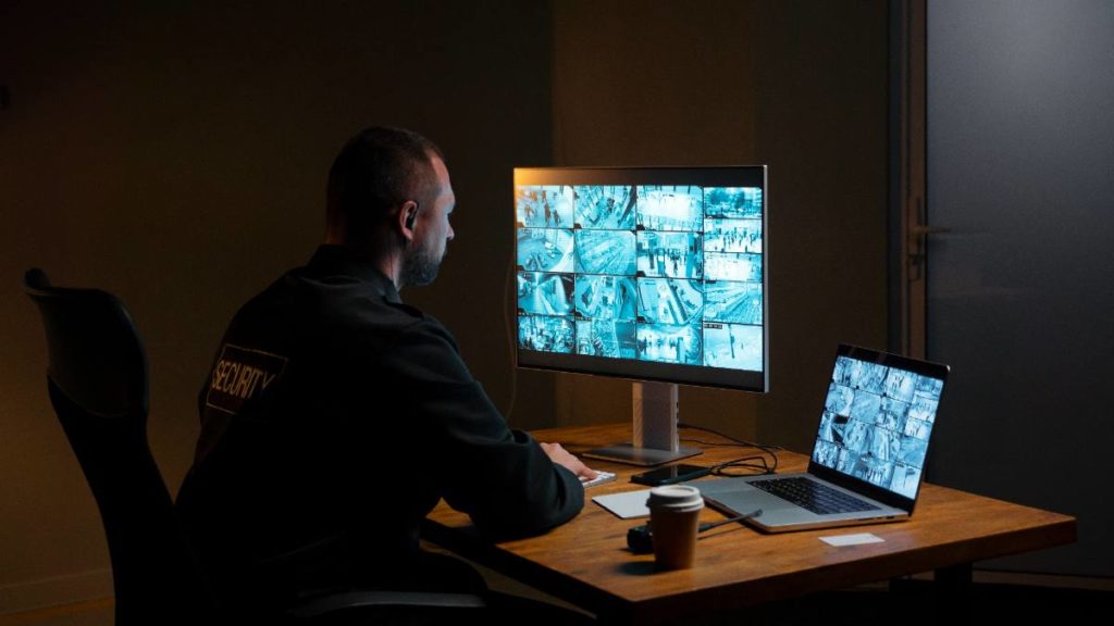 Coordenador de segurança a monitorizar câmaras de videovigilância em vários ecrãs numa sala de controlo