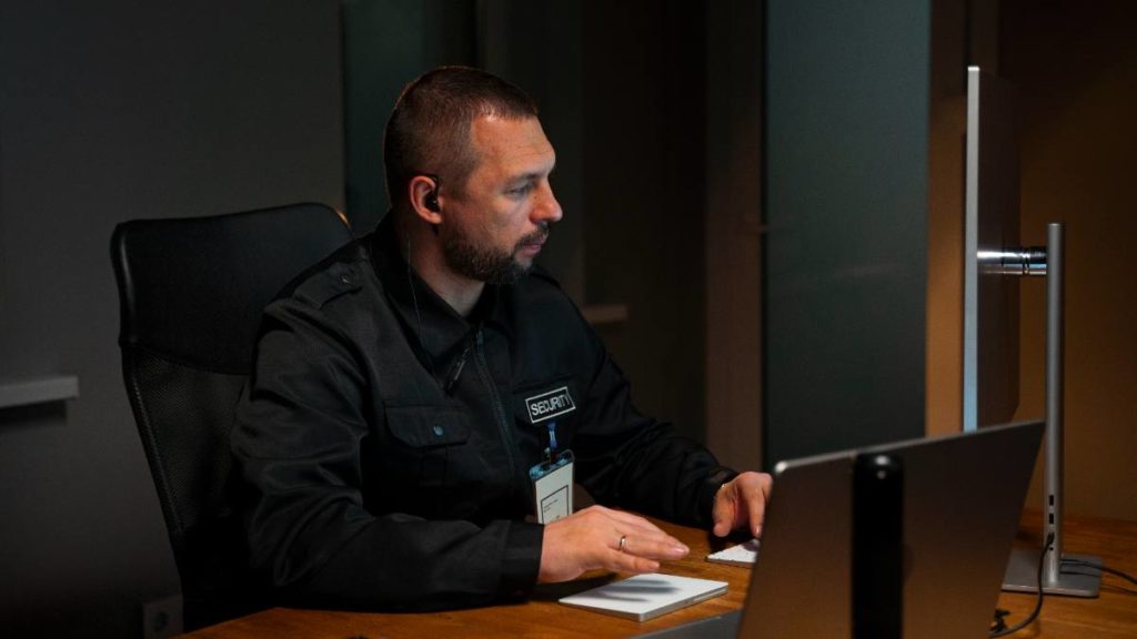 Supervisor de segurança privada a trabalhar num computador numa sala de controlo