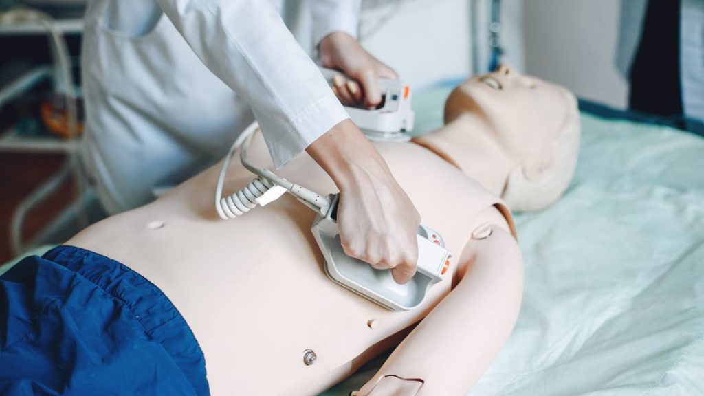Profissional a praticar o uso de um desfibrilhador num manequim de treino de suporte básico de vida